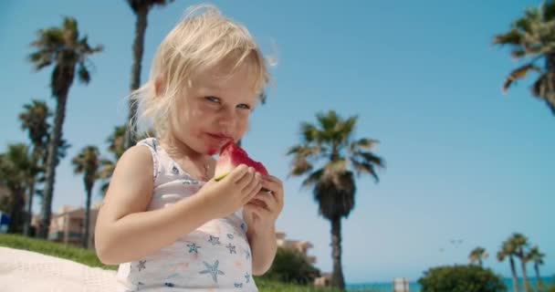 Niña con apetito come una sandía fresca en un día claro y soleado — Vídeo de stock