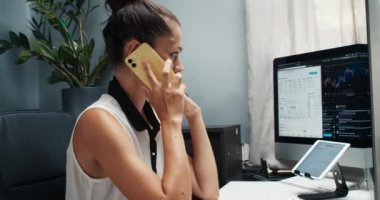 Kadın tüccar evden çalışır. Bir telefon görüşmesine cevap verir ve birkaç cihaz kullanır.