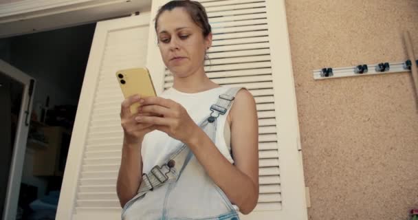 Νεαρή Καυκάσια γυναίκα που χρησιμοποιεί κίτρινο smartphone σε χρόνο φιδιού πλάνα χαμηλής γωνίας — Αρχείο Βίντεο