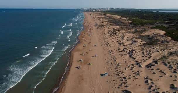 Dron letí pozpátku nad středozemním mořem a divokou pláží v létě při západu slunce — Stock video