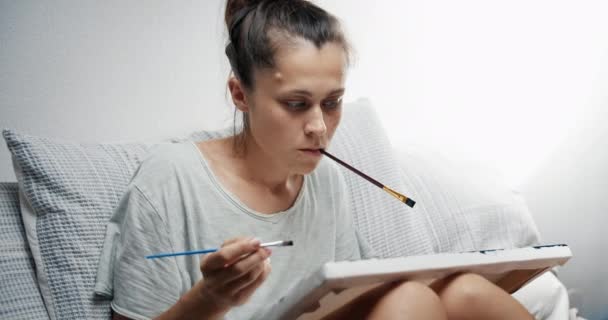 Giovane artista pittura tela nel suo soggiorno con pennello in mano — Video Stock