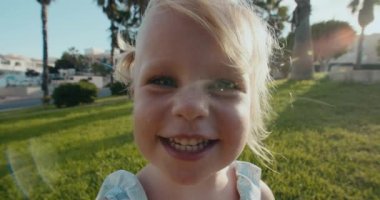 Kameraya bakıp parkta gülümseyen güzel bir kızın portresini yakından çek.