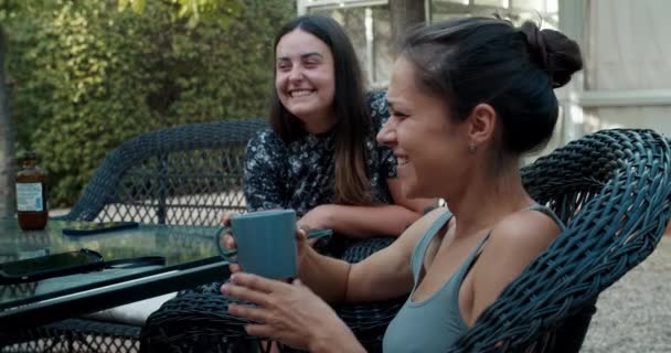 Deux jeunes femmes heureuses souriantes et parlant dans le patio de la maison rustique — Video