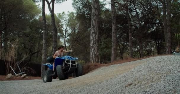 Giovane bella donna con figlio sta guidando quad nella foresta la sera — Video Stock