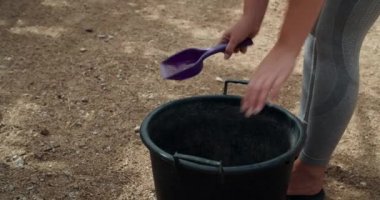 Genç çiftçi kadın kakadan tavuk kümesi temizliyor, çocuklar etrafta dolaşıyor.