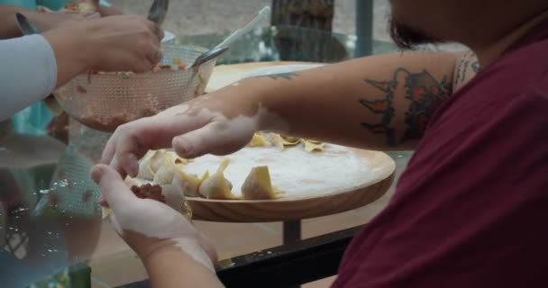 Διαφορετικοί άνθρωποι κάνουν ασιατικό φαγητό wonton μαζί τα χέρια των ανδρών κοντά — Αρχείο Βίντεο