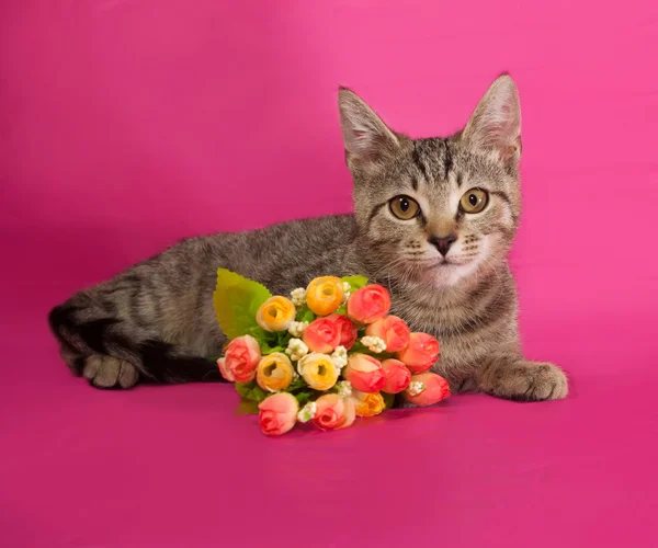 Gestreiftes Kätzchen mit Blumenstrauß auf rosa — Stockfoto
