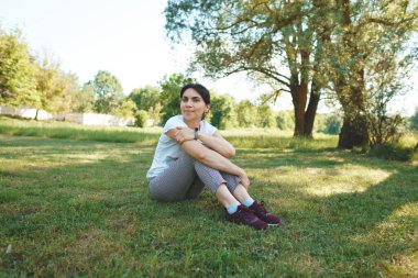 Gülümseyen kadın yeşil çimlerde dinleniyor.