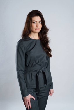 Koyu gri takım elbiseli kadın, beyaz arka planda kemer.