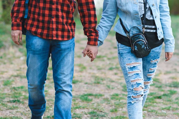 手をつないで公園を歩くジーンズのカップルは — ストック写真