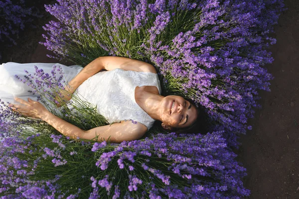 穿着白衣的笑女人躺在薰衣草花丛中 — 图库照片