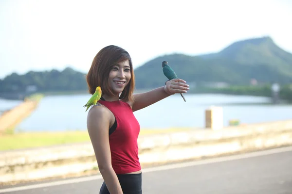 pretty woman pose and smile with green bird