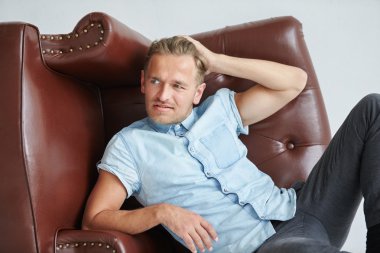 Acımasız adam kahverengi deri koltuk yanında yalan yere yan yatan koltuk, bir adam sandalyenin arkasında ellerini tutar