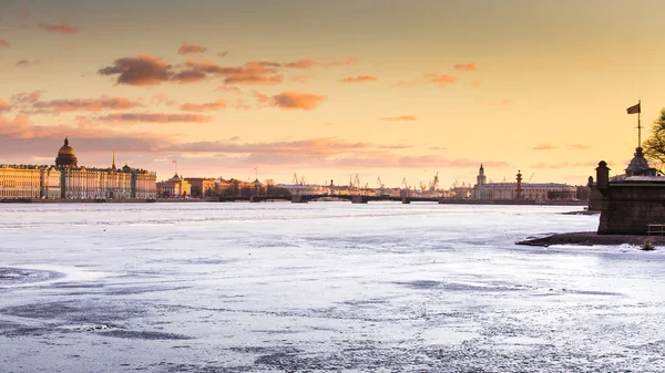 Rusia, San Petersburgo, 19 de marzo de 2016: La zona de agua del río Neva al atardecer, el Palacio de Invierno, el Puente del Palacio, la cúpula de la Catedral de San Isaac, nubes rosadas, río congelado — Foto de Stock