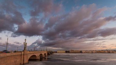 Rusya, Saint-Petersburg, 19 Mart 2016: pembe bulutlar üzerinde Troitsky sürüklenen köprüsünde, günbatımı, buz, donmuş Neva nehir, köprü üzerindeki trafik yaya yürüyerek Troitskiy