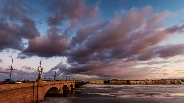 Россия, Санкт-Петербург, 19 марта 2016 года: Розовые облака над Троицким мостом на закате, дрейфующий лед, замерзшая Нева, движение по мосту, пешеходная прогулка, Троицкий — стоковое фото