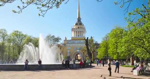 俄罗斯，圣彼得堡，2016年5月8日：在晴朗的天气，广场上的大喷泉，人们散步和庆祝五月假期，红色郁金香，绿树和草的海军大楼 — 图库视频影像