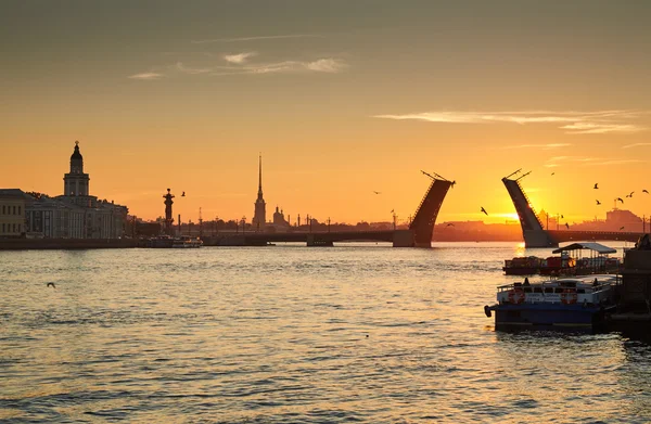 Russia, Saint-Petersburg, 03 July 2016: Closing of Palace Bridge at sunrise, the Peter and Paul Fortress Spike in the orange sky, Rostral colomn, ships, boats, the traffic beginning, sun, — Stock Photo, Image