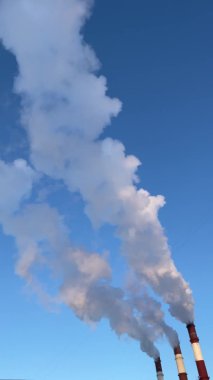 Kışın açık, güneşli ve dikey bir havada sıcak elektro istasyonunun borularından çıkan buhar.