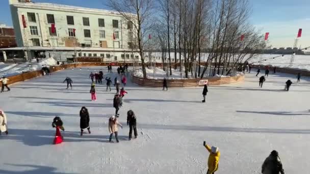 Ryssland, Sankt Petersburg, 22 februari 2021: Skridskobana på den tidigare växtens territorium, girlanger över skridskobanan, klar solig dag, Musiklekar, barnfamiljer och lyckliga par — Stockvideo