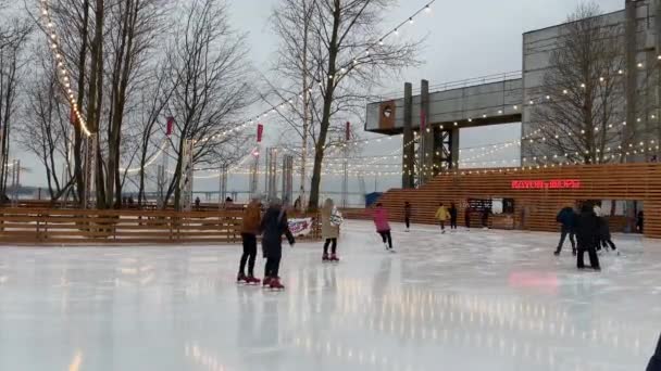 Rusland, Sint-Petersburg, 28 januari 2021: Schaatbaan op het grondgebied van de voormalige fabriek, slingers over een schaatsbaan, somber weer, Muziekstukken, gezinnen met kinderen en gelukkige stellen — Stockvideo