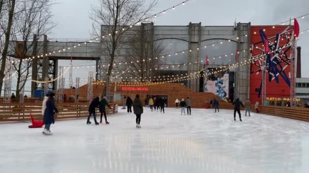 Rusland, Sint-Petersburg, 28 januari 2021: Schaatbaan op het grondgebied van de voormalige fabriek, slingers over een schaatsbaan, somber weer, Muziekstukken, gezinnen met kinderen en gelukkige stellen — Stockvideo