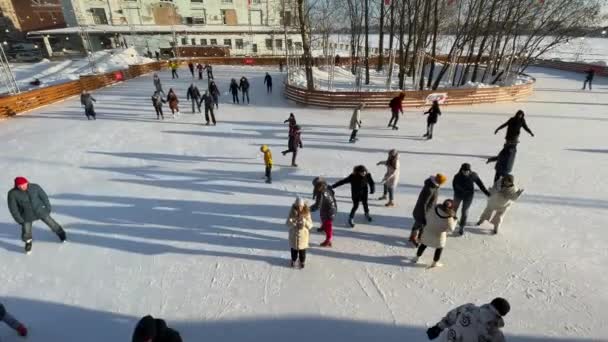 Rusland, Sint-Petersburg, 22 februari 2021: Schaatbaan op het grondgebied van de voormalige fabriek, slingers over de schaatsbaan, heldere zonnige dag, Muziekstukken, gezinnen met kinderen en gelukkige stellen — Stockvideo