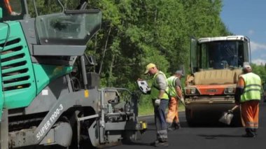 Rusya, St.Petersburg, 28 Haziran 2019: Yeni asfalt, özel arabalar, buz pateni pisti, ormandaki yol, yeşil ağaçlar, güneşli günler, işçiler, yeni asfalt yığınları 