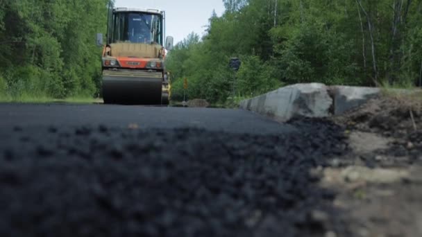 Russia, San Pietroburgo, 28 giugno 2019: posa della nuova asfalto, auto speciali, pista di pattinaggio, la strada nel bosco, foresta, alberi verdi, giornata di sole — Video Stock