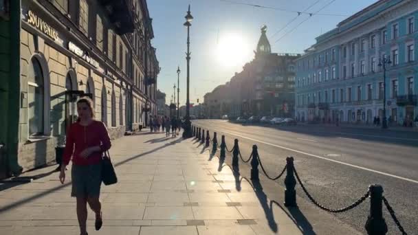 Rusia, San Petersburgo, 02 de junio de 2020: La casa de Zinger, torre alta, la arquitectura de Nevsky Prospect al atardecer durante la pandemia del virus Covid-19, peatones y coches, largas sombras de construcción — Vídeos de Stock