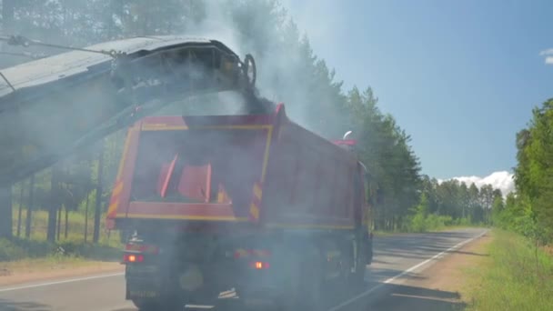 Russia, St.Petersburg, 28 June 2019: Roadwork on asphalt replacement, the car for removal of old asphalt, the conveyor, the road in the wood, a summer sunny day, special equipment — Stock Video