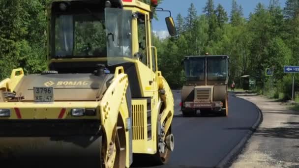 Rusko, Petrohrad, 28. června 2019: Položení nového asfaltu, speciální auta, kluziště, cesta v lese, les, zelené stromy, slunečný den — Stock video