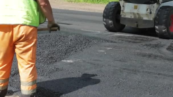 Росія, Санкт-Петербург, 28 червня 2019: Освоєння нового асфальту, спеціальні автомобілі, ковзанка, дорога в лісі, ліси, зелені дерева, сонячний день, робітники, стеки нового асфальту — стокове відео