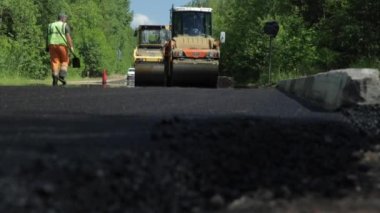 Rusya, St.Petersburg, 28 Haziran 2019: Yeni asfalt, özel arabalar, buz pateni pisti, ormandaki yol, yeşil ağaçlar, güneşli günler, işçiler, yeni asfalt yığınları 