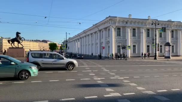 Russland, St.Petersburg, 02. Juni 2020: Die berühmte Anichkov-Brücke mit vier Pferden, Die Architektur des Newski-Prospekts bei Sonnenuntergang während der Pandemie des Virus Covid-19, Menschen überqueren die Straße, lange Schatten — Stockvideo