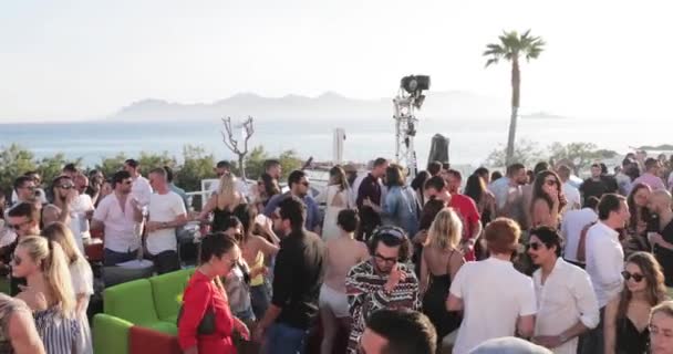 Francia, Cannes, 19 de mayo de 2017: la fiesta en una playa con mucha gente, el DJ el padre de un techno Carl Cox juega en 4 tocadiscos, manos arriba, puesta de sol, mar y montañas en el fondo — Vídeos de Stock