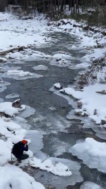 Mavi renkten dağ nehri, taşlar ve buzdan, fotoğrafçı resim yapıyor, arka planda karla kaplı dağlar, dikey video