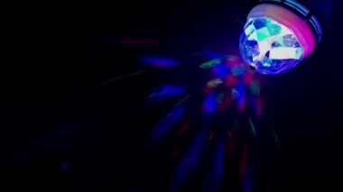 Cam çok renkli küre, farklı yönlerdeki farklı ışık ışınları ile döner, duvardaki çok renkli ışık demetleri