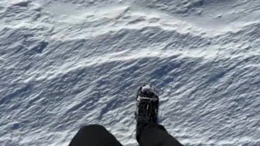 Siyah botlar karda açık ve güneşli bir havaya gider, botlar kar sırasında bozulur, bağcıklı botlar, siyah pantolonlar, üst manzara, kapalı