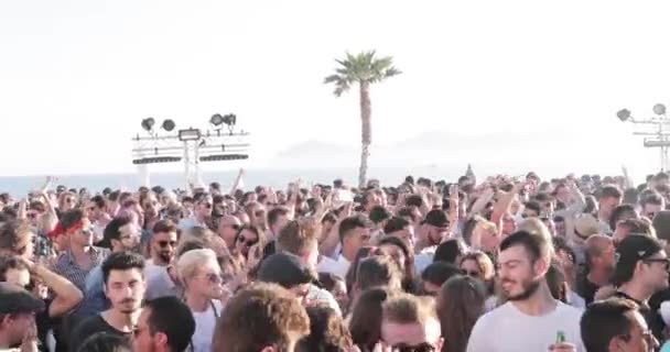 Franciaország, Cannes, 2017. május 19.: a parti a tengerparton sok emberrel, a DJ egy techno atyja Carl Cox játszik 4 lemezjátszón, kezek fel, naplemente, tenger és hegyek a háttérben — Stock videók