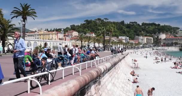 Francia, Niza, 15 de mayo de 2017: Paseo marítimo Anglais, Hermosa playa pública, Turistas, Sunbath People, Natación, Día soleado, La gente se sienta en las conocidas sillas azules, Ultra Alta Definición, UltraHD, 4K — Vídeos de Stock