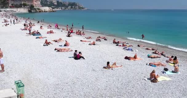 Francia, Niza, 15 de mayo de 2017: Paseo marítimo Anglais, Hermosa playa pública, Turistas, Sunbath People, Natación, Día soleado, La gente se sienta en las conocidas sillas azules, Ultra Alta Definición, UltraHD, 4K — Vídeos de Stock