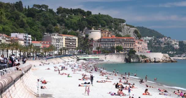 Francia, Niza, 15 de mayo de 2017: Paseo marítimo Anglais, Hermosa playa pública, Turistas, Sunbath People, Natación, Día soleado, La gente se sienta en las conocidas sillas azules, Ultra Alta Definición, UltraHD, 4K — Vídeos de Stock