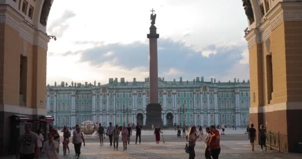 ロシア、サンクトペテルブルク、 2020年6月9日:利用された馬車は、日没時に宮殿広場にあり、アレクサンドリアの列と冬の宮殿を背景に、それは多くの観光客、オブジェクトの長い影です。 — ストック動画