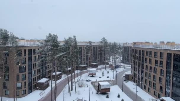 Russland, St.Petersburg, 19. Januar 2021: Der schöne, gut geplante Hof einer Wohnsiedlung im Wald, es schneit, schneebedeckte Bäume, eine schöne Fassade, große Fenster, ein Kinderspielplatz — Stockvideo