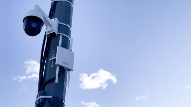 Russland, 22. März 2021: Die Überwachungskamera auf einer Metallsäule, ein Router einer drahtlosen Kommunikation mit Antennen, der blaue Himmel auf einem Hintergrund — Stockvideo
