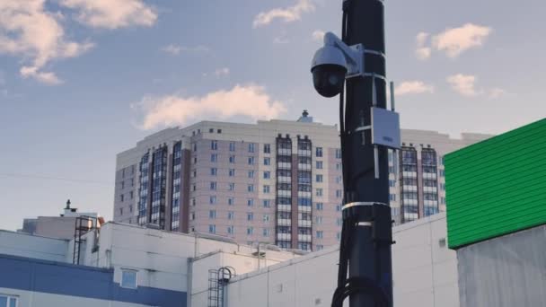 Россия, 22 марта 2021 г.: Камера наблюдения на металлической колонне, маршрутизатор беспроводной связи с антеннами, голубое небо и котлы на заднем плане — стоковое видео