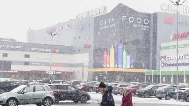 Rusko, Petrohrad, 18. března 2021: Silný sníh v městském ruchu, parkoviště u obrovského nákupního centra, sněhová bouřka, sněhová bouřka, na budově pestrobarevné cedule — Stock video