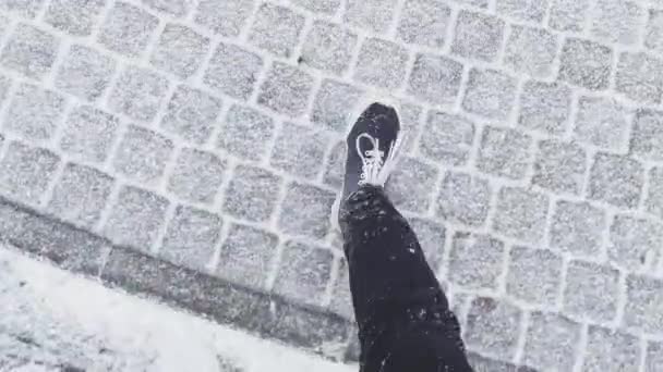 Mans botas negras van en la nieve a un clima nublado helada clara, El camino está pavimentado por una baldosa de piedra, zapatillas de deporte, botas fallan durante la nieve, botas con cordones, pantalones de color negro, la vista superior, primer plano — Vídeos de Stock