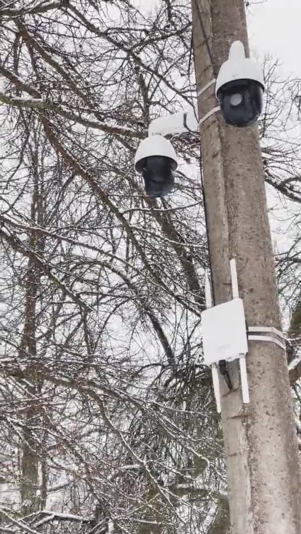 Rosja, Sankt Petersburg, 22 marca 2021 r.: Pionowe nagranie z kamery monitorującej wisi na konkretnej kolumnie, routerze komunikacji bezprzewodowej z antenami, drzewach liściastych na tle — Wideo stockowe